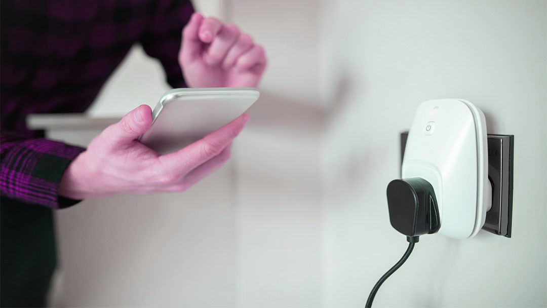 uno de los enchufes inteligentes blanco controlado por una persona con smartphone
