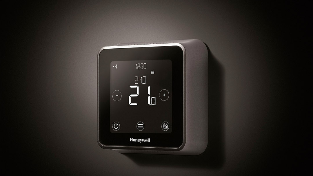 uno de los termostatos honeywell negro y gris sobre pared oscura