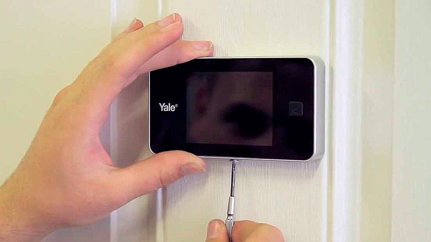 Manos instalando una mirilla digital