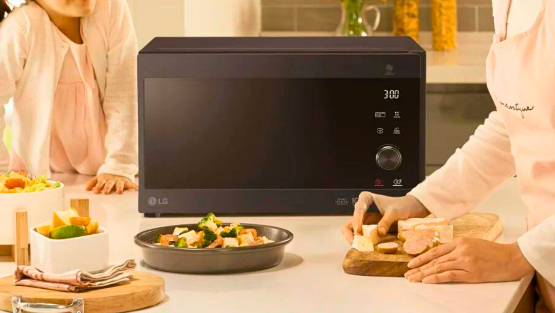 Microondas ubicado en la encimera de la cocina junto a los alimentos