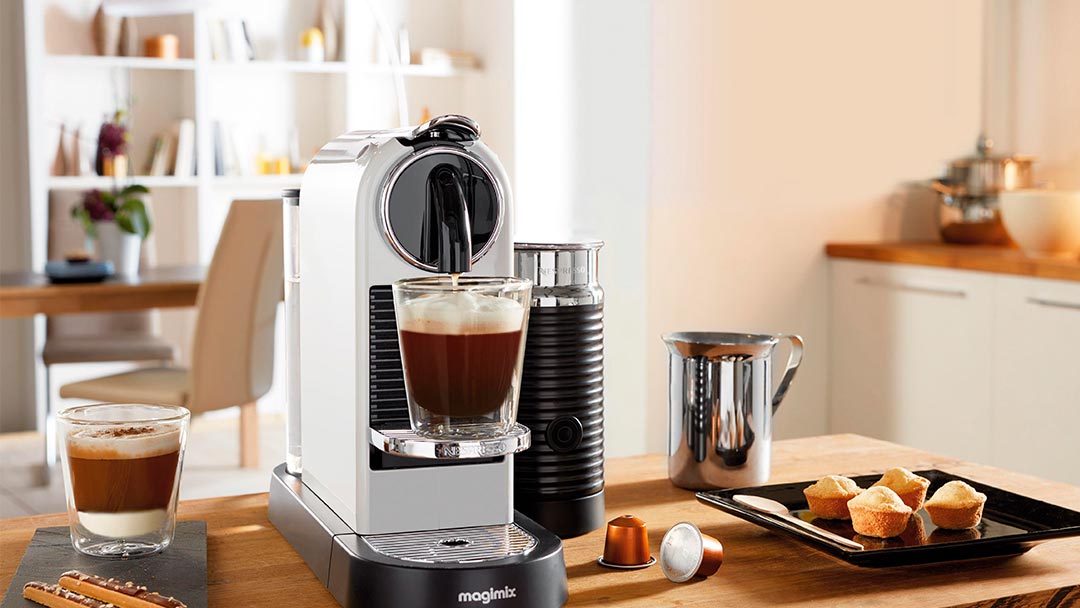 Una de las cafeteras de cápsulas en color blanco preparando cafés en la cocina