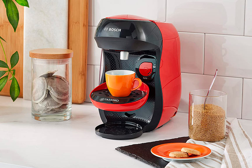 Cafetera roja y negra sirviendo café en la encimera de la cocina