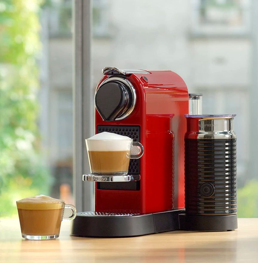 Cafetera de cápsulas roja ubicada en la encimera preparando café