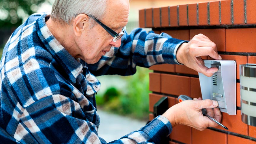 hombre de edad avanzada realizando la instalación de un videoportero