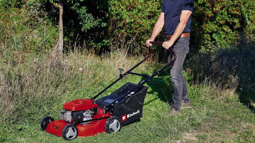 hombre manejando cortacésped gasolina de color rojo en el jardín