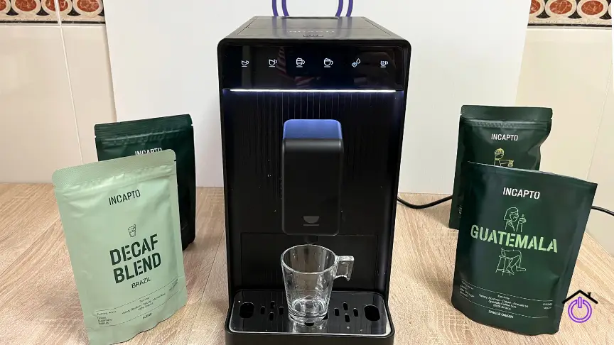 cafetera negra con bolsas de grano de café y taza