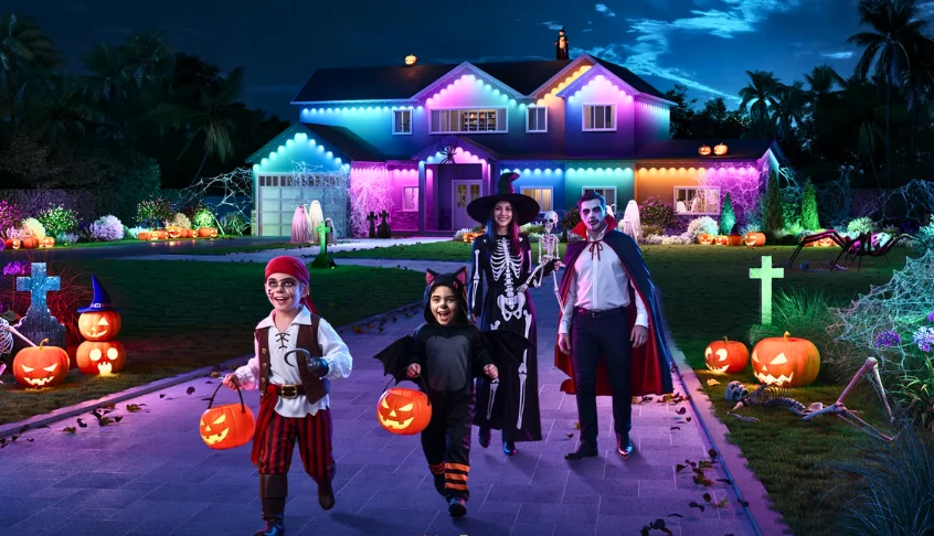 famila disfrazada en Halloween y casas iluminadas de colores por la noche